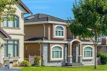 Row of nice houses with green lawns and scattered trees and shrubs.