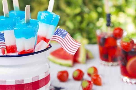 4th of July celebration with strawberries, watermelon slices, red fruit punch, and flag-colored popsicles with mini-flags around.